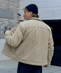 Hombre con casaca corduroy beige polo negro con gorra negra de espalda