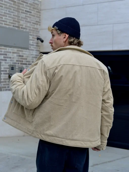 Hombre con casaca corduroy beige polo negro con gorra negra de espalda