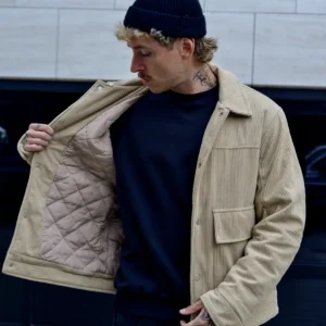 Hombre con casaca corduroy beige polo negro con gorra negra enseña forro casaca